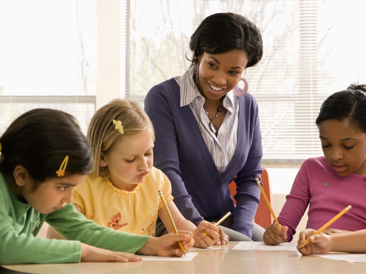 teacher assisting young students