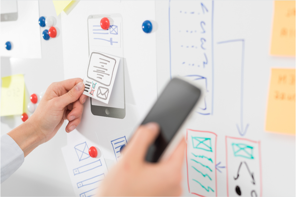 writing on sticky notes on a clipboard in front of laptop